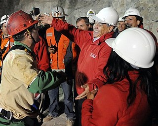 In this photo released by the Chilean presidential press office, Chile's President Sebastian Pinera, fifth right, open his arms to hug rescued miner Mario Sepulveda,after Sepulveda was rescued from the collapsed San Jose gold and copper mine where he was trapped with 32 other miners for over two months near Copiapo, Chile, early Wednesday Oct. 13, 2010. (AP Photo/Jose Manuel de la Maza, Chilean presidential press office)