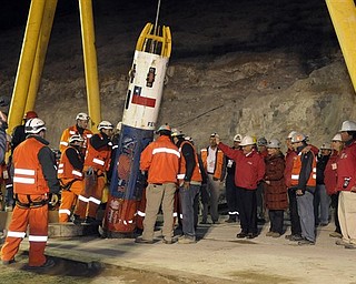 In this photo released by the Chilean presidential press office, Chile's President Sebastian Pinera, center right in red jacket, waves to rescue worker Manuel Gonzalez Paves as he is lowered into the mine in the capsule to begin the rescue of 33 trapped miners at the San Jose Mine near Copiapo, Chile, Tuesday Oct. 12, 2010. The first of 33 trapped miners is expected to be lifted to the surface late Tuesday after surviving more than two months below ground. (AP Photo/Alex Ibanez, Chilean presidential press office)