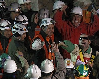 Chile's President Sebastian Pinera, top right, cheers as rescued miner Mario Sepulveda Espina, right, salutes after being rescued from the the collapsed San Jose gold and copper mine where he was trapped with 32 other miners for over two months near Copiapo, Chile, early Wednesday Oct. 13, 2010.(AP Photo/Roberto Candia)