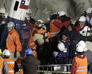Rescued miner Florencio Antonio Avalos Silva embarces one of the rescue workers as his wife Monica and son Byron, center right, look on next to President Sebastian Pinera, second from right, after he arrived to the surface from the collapsed San Jose gold and copper mine where he was trapped with 32 other miners for over two months near Copiapo, Chile, early Wednesday, Oct. 13, 2010.(AP Photo/Jorge Saenz)