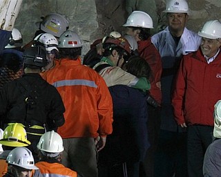 Chile's President Sebastian Pinera, right, looks on as miner Florencio Antonio Avalos Silva embraces his wife Monica after he was rescued from the collapsed San Jose gold and copper mine where he was trapped with 32 other miners for over two months near Copiapo, Chile, early Wednesday, Oct. 13, 2010.(AP Photo/Roberto Candia)