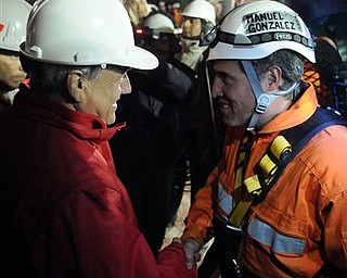 In this photo released by the Chilean presidential press office, Chile's President Sebastian Pinera, left, shakes hands with rescuer Manuel Gonzalez before he's lowered into the mine where miners are trapped to begin their rescue at the San Jose mine, near Copiapo, Chile, Tuesday, Oct. 12, 2010. (AP Photo/Alex Ibanez, Chilean presidential press office)