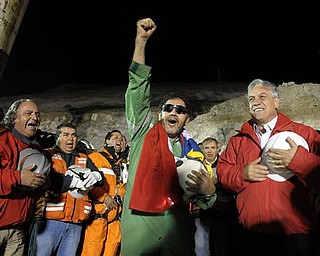In this photo released by the Chilean Presidential Press Office, the last miner to be rescued, Luis Urzua, center, gestures as Chile's President Sebastian Pinera, right, looks on after his rescue from the collapsed San Jose gold and copper mine where he had been trapped with 32 other miners for over two months near Copiapo, Chile, Wednesday Oct. 13, 2010. The 69-day underground ordeal reached its end Wednesday night after 33 trapped miners were hauled up in a cage through a narrow hole drilled through 2,000 feet of rock. (AP Photo/Alex Ibanez, Chilean Presidential Press Office)