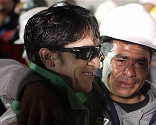 In this photo released by the Chilean government, miner Ariel Ticona Yanez, left, smiles after being pulled out of the San Jose gold and copper mine where he had been trapped with 32 other miners for over two months near Copiapo, Chile, Wednesday Oct. 13, 2010. (AP Photo/Chilean Government, Hugo Infante)