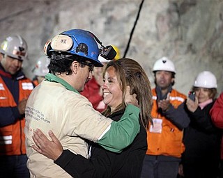 In this photo released by the Chilean government, miner Raul Bustos, left, embraces an unidentified woman after after being rescued from the collapsed San Jose gold and copper mine where he had been trapped with 32 other miners for over two months near Copiapo, Chile, Wednesday Oct. 13, 2010. (AP Photo/Chilean Government, Hugo Infante)