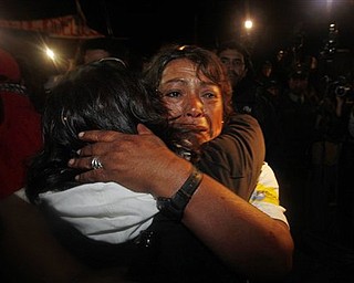 Maria Segovia, right, sister of freed miner Dario Segovia, embraces an unidentified person as relatives and friends of the freed 33 miners celebrate the end of the successful rescue operation at the camp outside the San Jose mine near Copiapo, Chile, Wednesday Oct. 13, 2010. The 69-day underground ordeal reached its end Wednesday night after 33 trapped miners were hauled up in a cage through a narrow hole drilled through 2,000 feet of rock. (AP Photo/Natacha Pisarenko)