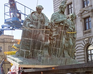 Geoffrey Hauschild|The Vindicator.Construction workers work to remove the 3 figure statue from the top of the Mahoning County Courthouse in order to perform repairs on the deteriorating pedestal that supports them.