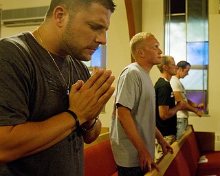 Geoffrey Hauschild|The Vindcator.8.4.2010.OVTC Director of Operations Bob Pavlich prays alongside residents Anthony Sanders and Austin Henderson during the group's Wednesday night weekly church service at Youngstown Christian Assembly.