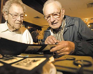 Charles Butler, 90, left, of Liberty, and Frank R. Swast, 85, of North Carolina, look over old World War II photos. Butler was Swast’s commanding officer on a ship when they both served in the Navy. They haven’t seen each other in more than 60 years. Efforts by Swast’s family here helped bring them together for a reunion Wednesday at the Springfield Grille in Boardman.