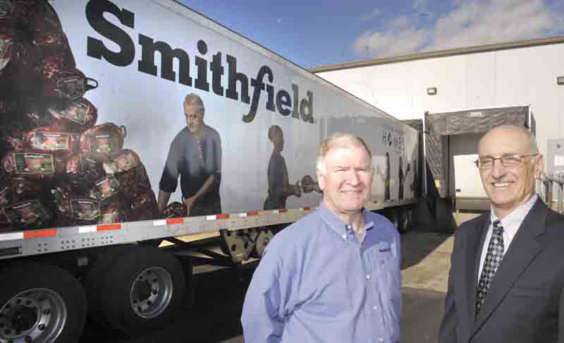 Dennis Pitman, left, Smithfield Foods’ director of corporate communications, and Michael Iberis, executive director of Second Harvest Food Bank of the Mahoning Valley, stand beside an 18-wheeler that delivered 30,000 pounds of pork products donated to the food bank by Smithfield and the United Food and Commercial Workers Union.

