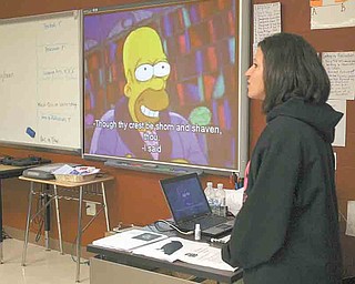 At left, ninth-grade teacher Rochelle Morelli makes comments to her class during a video clip from an episode of “The Simpsons,” which featured a reading of Edgar Allan Poe’s “The Raven.” Morelli’s students used high-tech learning tools to teach the fourth-graders about Edgar Allan Poe and his classic poem. Morelli’s class is studying Gothic literature.