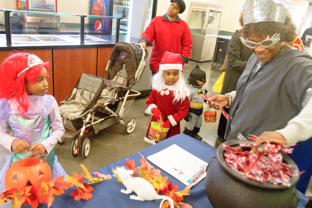 Michalene Hughley granbs candy for Kalia Anderson, 6 (left), and Nevaeh Shouse, 4, and at the Covelli Centre on Saturday afternoon. Quander Shouse, 2, is dressed as batman, and Nevaeh and Quander's mother Lavertta Shouse is pushing the stroller.