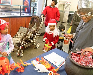 Michalene Hughley granbs candy for Kalia Anderson, 6 (left), and Nevaeh Shouse, 4, and at the Covelli Centre on Saturday afternoon. Quander Shouse, 2, is dressed as batman, and Nevaeh and Quander's mother Lavertta Shouse is pushing the stroller.