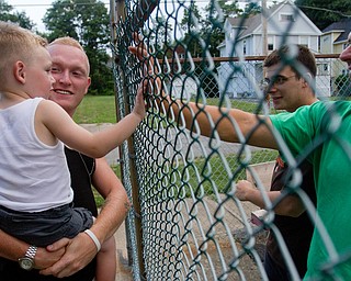 Geoffrey Hauschild|The Vindicator.7.24.2010.OVTC resident Anthony Sanders introduces his son, Michael, to fellow residents Aaron Repko (second from right) and intern, Jesse Repko (right), outside of OVTC on Youngstown's North Side. The Repkos are brothers.