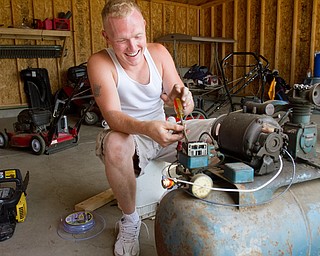 Geoffrey Hauschild|The Vindicator.7.26.2010.OVTC resident Anthony Sanders works to repair a donated air compressor in Pastor Bob Pavlich's garage while fellow members work in the nearby Arlington Heights area.