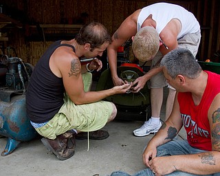 Geoffrey Hauschild|The Vindicator.7.26.2010.Darren Vath, Anthony Sanders and John Anderson, work on a broken piece of landscaping equipment at Pastor Bob Pavlich's garage during landscaping work at nearby Arlington Heights.