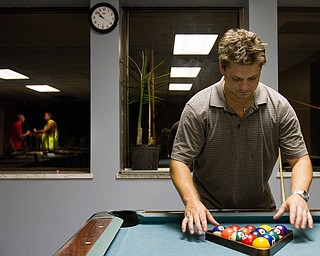 Geoffrey Hauschild|The Vindicator .8.6.2010.Michael Malott racks balls for a game of pool, during his free time at Ohio Valley Teen Challenge while the window reflects residents playfully wrestling in the background.