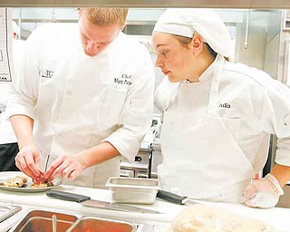 Julia Coburn of South Range, watches as chef Matt Putzier prepares a plate presentation at The Bistro. The new restaurant at the Mahoning County Career and Technical Center on Palmyra Road in Canfield will have its grand opening next week.
