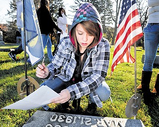 In this Nov. 11, 2010 photo, State College Area High School student Melody Ireland looks at a tombstone at Spring Creek Presbyterian Cemetery in State College, Pa. Her class was gathering names of veterans to do further research to try and find the soldiers stories. (AP Photo/Centre Daily Times (Knight Ridder), Nabil K. Mark) MAGS OUT, NO SALES
