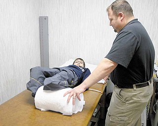 Ron Santiago, physical therapist at Youngstown Orthopaedic Associates, works with Kolya Denykin on exercises to improve his muscle tone so he is better able to balance on his new prosthetic legs.