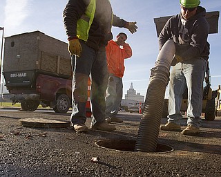 Workers with Marucci and Gaffney Excavating of Youngstown, Dave Mill of Brookfield, Din DiFabio of New Middletown and John Fedoruk of Austintown, remove a sump pump while completing sanitary and road work along Fifth Avenue in Youngstown. (Geoffrey Hauschild | The Vindicator)