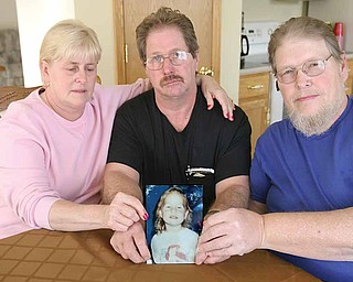 Family members of Jessica Ballew hold a portrait of her. They are, from left, Connie Ressler, Jessica’s aunt; Virgil Ballew, her father; and Steve Ballew, her uncle. Gov. Ted Strickland’s clemency to the killer of Jessica has angered the family.