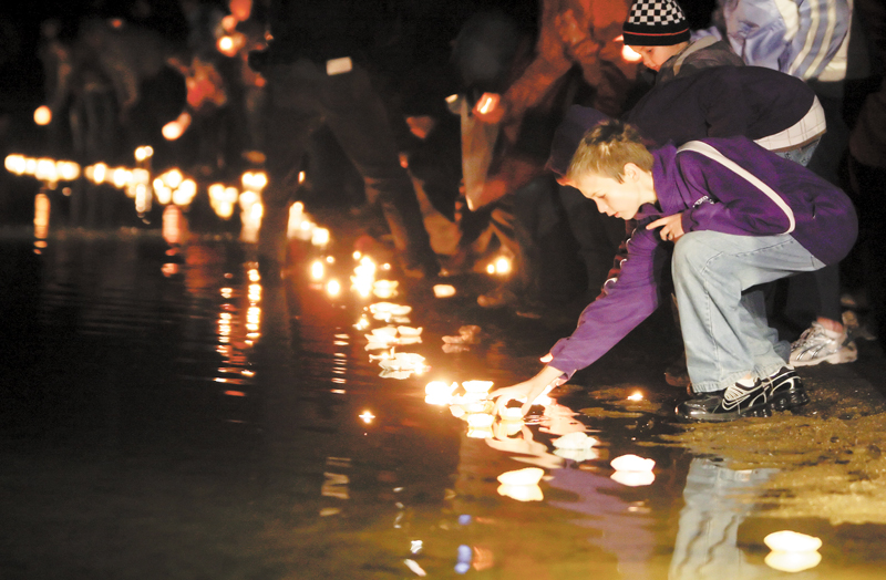 Local residents place candles in the lake during a vigil for the three missing people who were found dead, Thursday, Nov. 18, 2010, in Howard, Ohio.