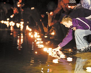Local residents place candles in the lake during a vigil for the three missing people who were found dead, Thursday, Nov. 18, 2010, in Howard, Ohio.