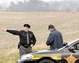 A sheriff's deputy directs traffic away from one of the entrances to Kokosing Lake where three bodies were found while talking with a local resident Thursday, Nov. 18, 2010, in Fredericktown, Ohio. Three people who vanished from a blood-spattered home more than a week ago were found dead inside a hollow tree Thursday, days after the teenage daughter of one of the victims was rescued _ bound and gagged _ from the basement of an ex-convict who worked as a tree-trimmer.