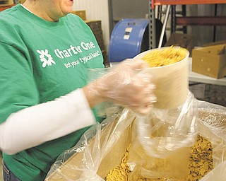 Cup upon cup of bulk cereal is placed in bags by Casey Martin, who was among Charter One Bank employees who volunteered at Second Harvest Food Bank of the Mahoning Valley on Tuesday. 