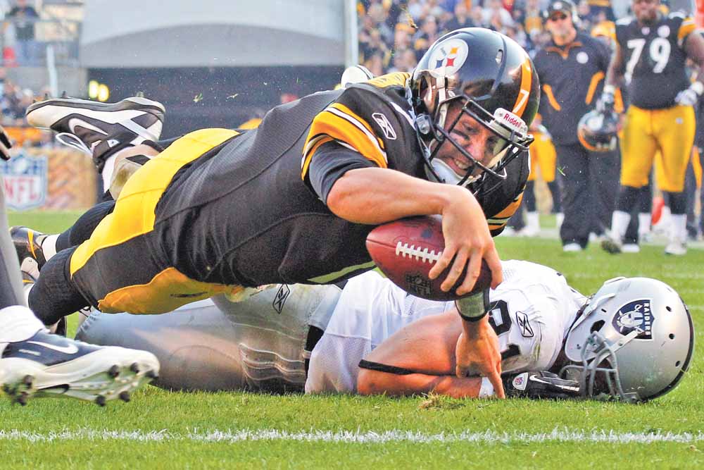 Pittsburgh Steelers quarterback Ben Roethlisberger, top, dives into the end zone over Oakland Raiders' Trevor Scott for a second-quarter touchdown during an NFL football game in Pittsburgh, Sunday, Nov. 21, 2010. (AP Photo/Gene J. Puskar)