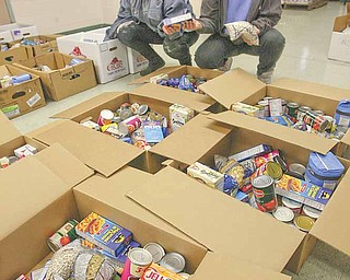 Geri Sterbian, left, and Cheri Douglas, volunteers for Neighborhood Ministries and twin sisters, double up to make sure each Thanksgiving box gets an equal amount of food. Volunteers packed the boxes Monday at the agency’s Campbell offices for 75 families who need supplies for the holiday.