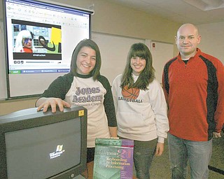 Alli Fonce (left) and Lisa Holmes, both seniors at Girard High, with their teacher, Jamie Williams. stand in front of the story boards that became the video, “Just Learn,” a parody of Lady Gaga’s “Just Dance.” The video, which was conceived, cast, filmed, edited and produced by GHS digital media students, is one of five finalists in the 2010 eInstruction Classroom Makeover Contest.