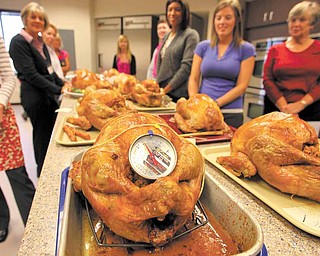 Trainees stand behind their cooked turkeys awaiting critique during training for Butterball talk-line employees on October 20, 2010, in Naperville, Illinois. 