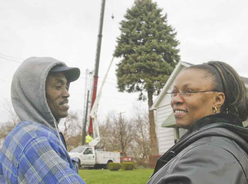 Rubey and Donna Taylor watch as a large blue spruce is cut from the yard of their home on Clay Street on Youngstown’s East Side on Wednesday. They donated the tree to the city to be used as the city Christmas tree. Donna Taylor said she was excited and blessed to have her tree selected for the honor.