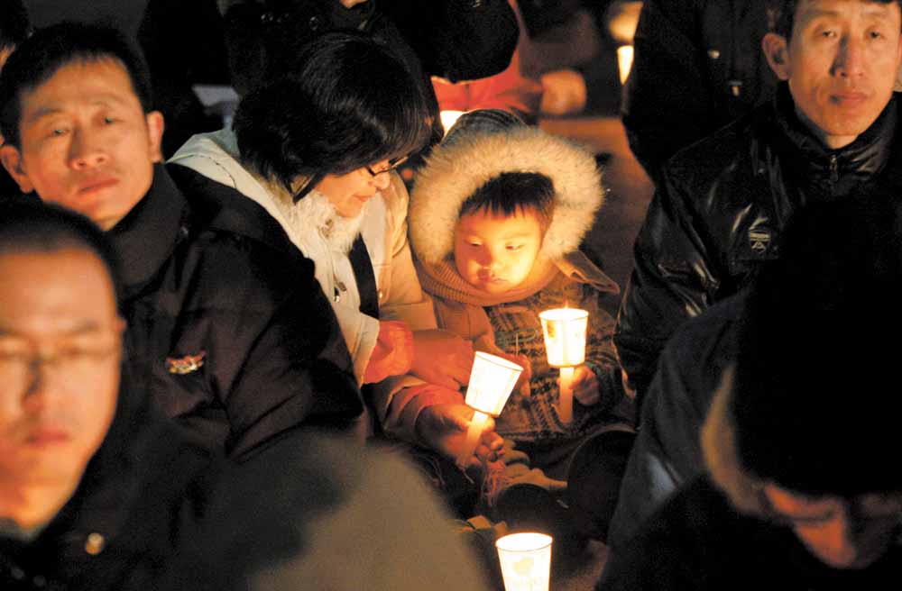 A South Korean child and mom hold candles during a rally against the U.S.-South Korea joint military exercise in Seoul, South Korea, Sunday, Nov. 28, 2010. China tried Sunday to defuse tension over a recent North Korean attack on South Korea by proposing an emergency meeting in Beijing, hours after the U.S. and South Korea launched naval war games in a united show of force.