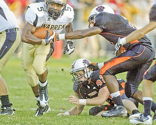 Harding's Demond Hymes gets past Howland's Tony Osborne and Dan Russell during first quarter action Friday at Howland.
