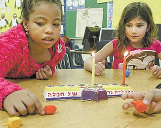 Sapphire Cathey, left, and Millie Heschmeyer, first-graders at Akiva Academy in Youngstown, spin dreidels, the Yiddish word for tops. Dreidels are part of the fun at Hanukkah, which began at sundown Wednesday. The eight-day festival continues until sundown next Thursday.