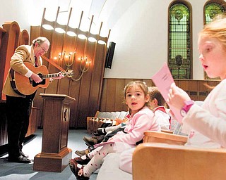 Lily Weiss (right), 6, of Canfield, and Saadyiah Leff (second from right), 2, of Cortland, sing Hanukkah themed songs as Rabbi Franklin Muller plays guitar during a Hanukkah celebration at Rodef Sholom in Youngstown on Sunday evening.