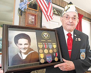 Alfred “Al” Gaskell of Howland, a member of the Pearl Harbor Survivors Association Mahoning Chapter 5, holds a display of the decorations he received from his service in the Navy in World War II. Included is a picture of himself in his Navy uniform from 1941.