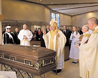 Bishop George V. Murry of the Diocese of Youngstown, center, blesses Monsignor Thomas F. Kelly during a Mass of Christian burial Monday morning at St. Christine Church in Youngstown. Monsignor Kelly, who died Nov. 30, was pastor emeritus of the church.