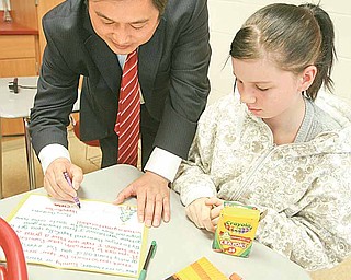 Deng Zhongqing, signs a holiday card that Chelsea Begeot is making in an English class at Girard Junior/Senior High School for overseas service personnel. Deng is in the United States through the Chinene Exchange Initiative, which allows 12 Chinese and 12 American educators to spend two weeks in each other’s country. Louise Mason, junior high principal, will go to China in the spring.