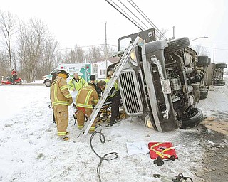 Lane Life Trans paramedics and firefighters from Cardinal Joint Fire District remove the driver from a tractor trailer that overturned Tuesday at the intersection of Leffingwell Road and U.S. Route 62, Canfield.