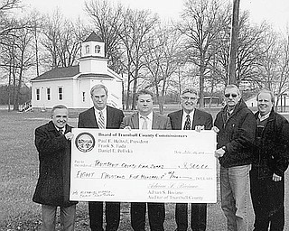 Commissioners raise the roof: Trumbull County commissioners recently presented a check for $8,500 to the Trumbull County Fair Board for the installation of a new roof and some panels on the 1848 Disciples of Christ Church. A symbolic big check for the big project was presented by the commissioners, from left, Frank Fuda, Paul Heltzel and Dan Polivka, to members of the fair board, Richard R. Roscoe, president; and Dick Turner and Ken Kubala, directors. The church, shown in the background, was moved in 1973 from the corner of Everett Hull and Hoagland Blackstub roads in Bazetta to the Trumbull County Fairgrounds.