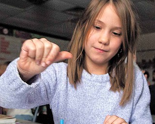 Jackson-Milton Elementary students Raenah Rader, 8, and Dalton Lockner, 9, play with a dreidel as part of an educational presentation on the history and customs of the Jewish holiday Hanukkah.