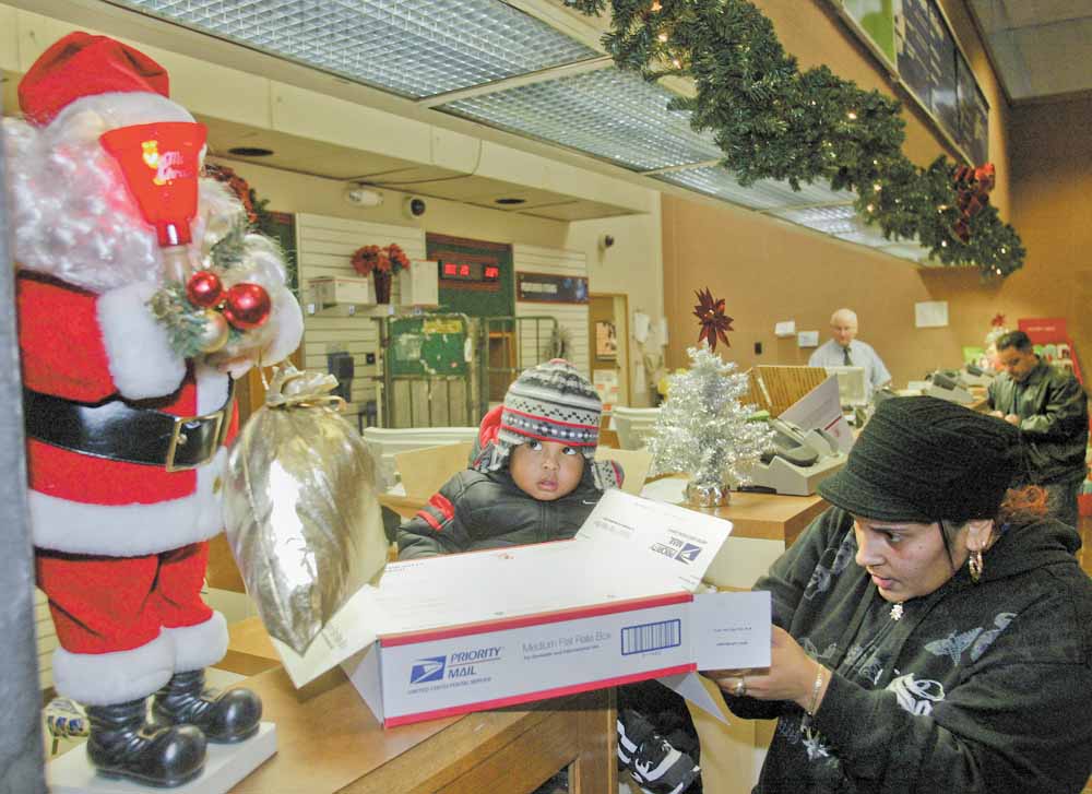 Maria Ruiz and her son Angel, 1, both of Youngstown, prepare to mail a package at theYoungstown Post Office Monday. Monday was one of the busiest postal days of the year.