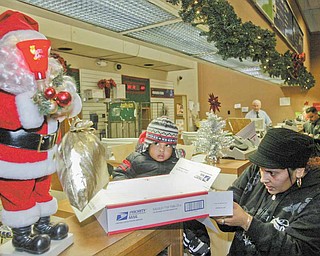 Maria Ruiz and her son Angel, 1, both of Youngstown, prepare to mail a package at theYoungstown Post Office Monday. Monday was one of the busiest postal days of the year.