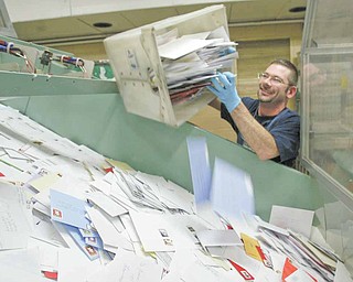 Youngstown Post Office employee Carl Flesher dumps a bind of mail onto a conveyor belt.