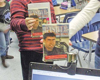 Fourth-grader Justin Cool holds a copy of a book called Basher Five-two that students in his class read. Justin wanted to know if Reservist Geoff Clark, on the screen, had read the true story of F-16 fighter pilot Scott O’Grady.