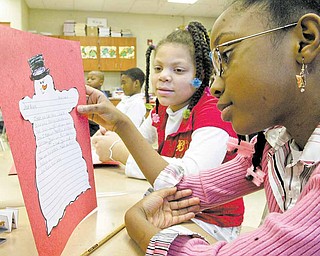Taft Elementary School fourth graders Tanesha Bryant, left, and Tejhae Glenn look over letters they wrote to military personnel serving in Afghanistan. The letters were a writing project in teacher Laurie McEwans’s class at the Youngstown school.